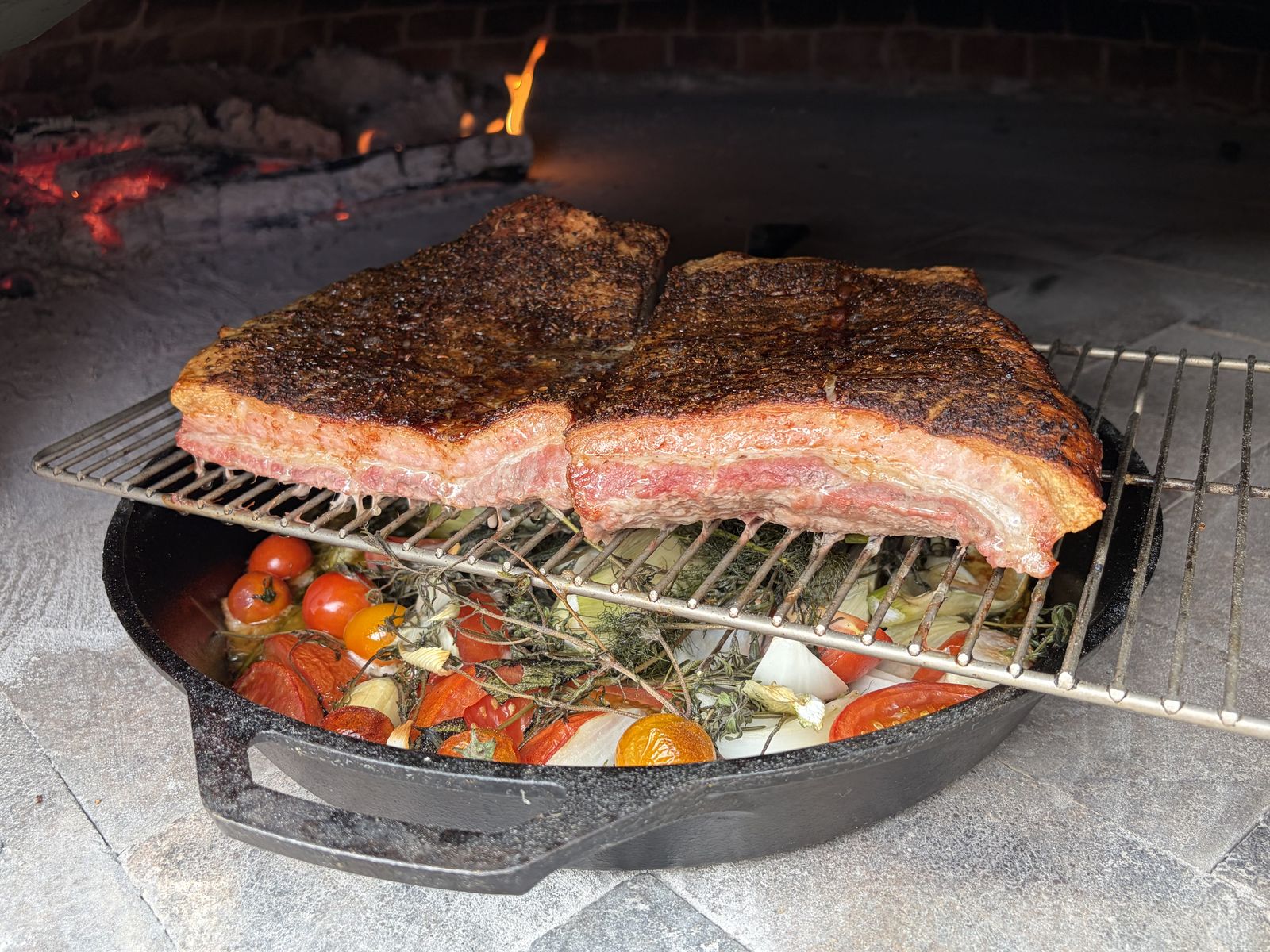 Pork belly roasting over vegetables in the wood-fired oven